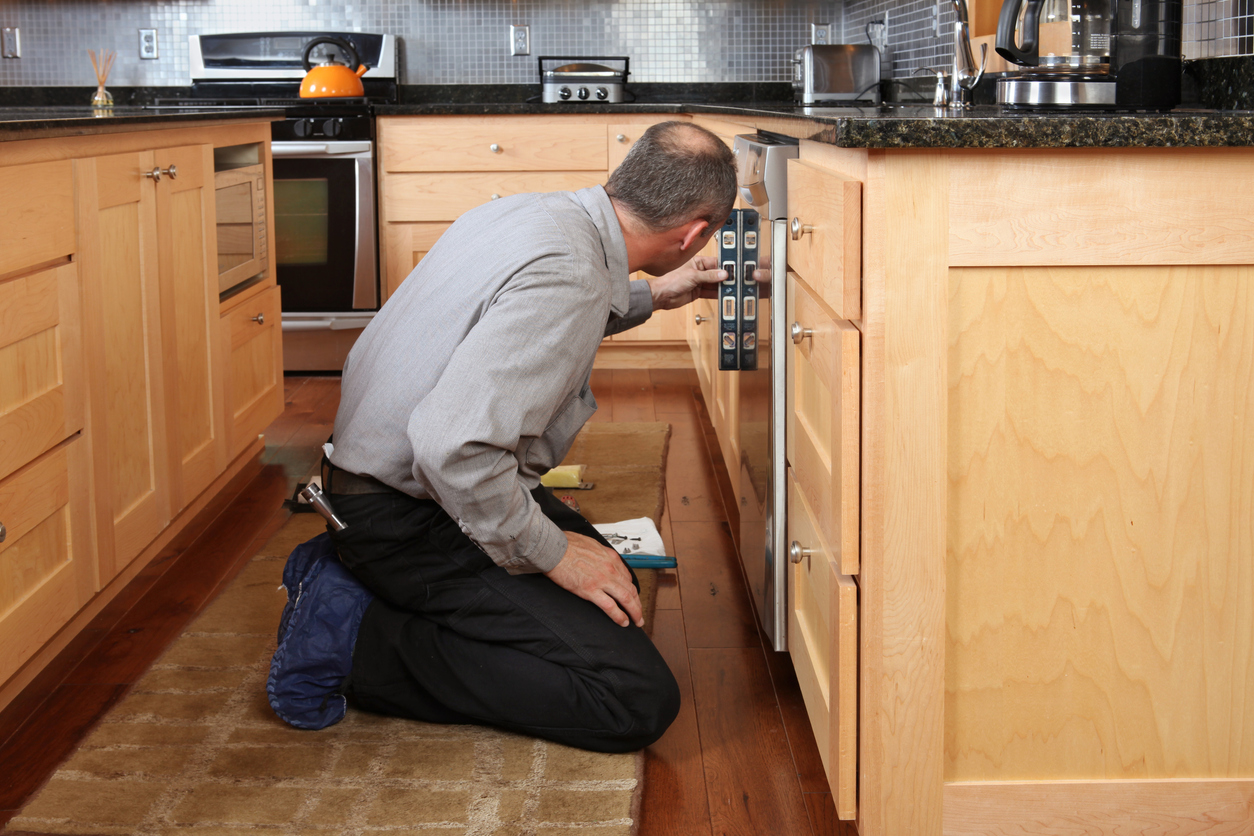 An appliance technician leveling a dishwasher door